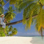 mujer sentada sobre palmera, Sun Aqua Vilu Reef